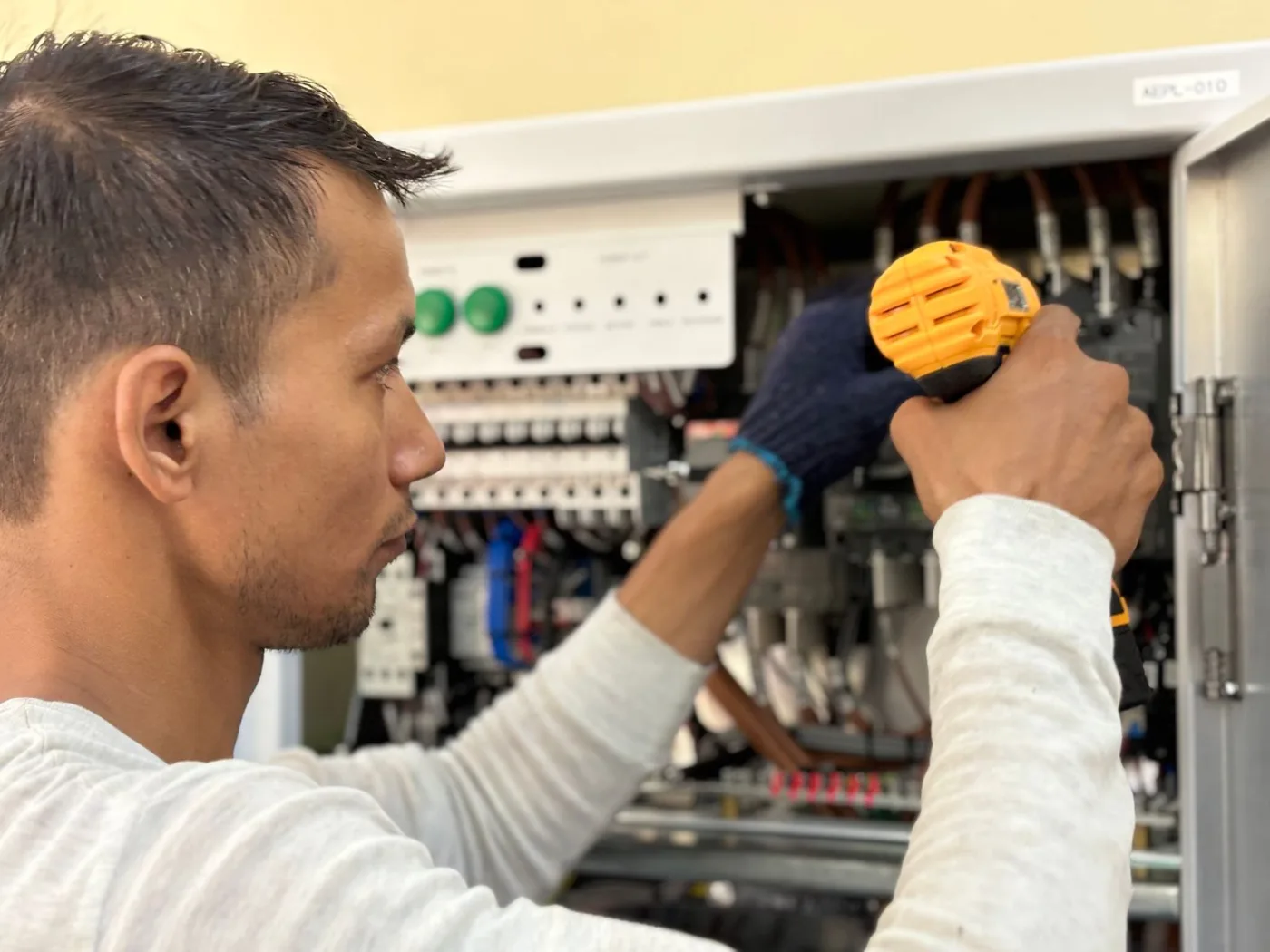Electrician working inside an electrical control panel
